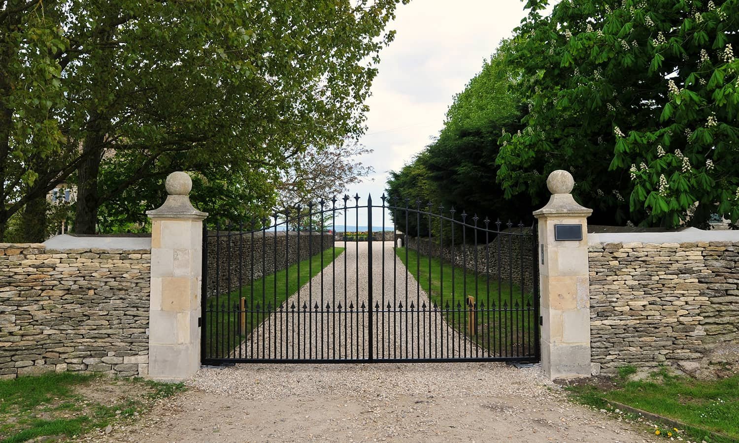Double swing driveway gate between masonry pillars
